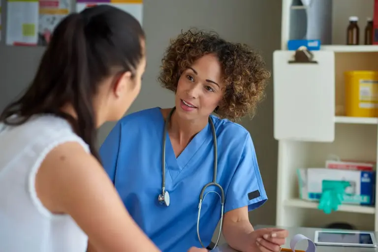 Female nurse talking with a patient during a consultation in a medical clinic.