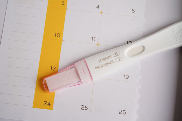 Positive home pregnancy test on a calendar representing fertility timelines and early pregnancy.
